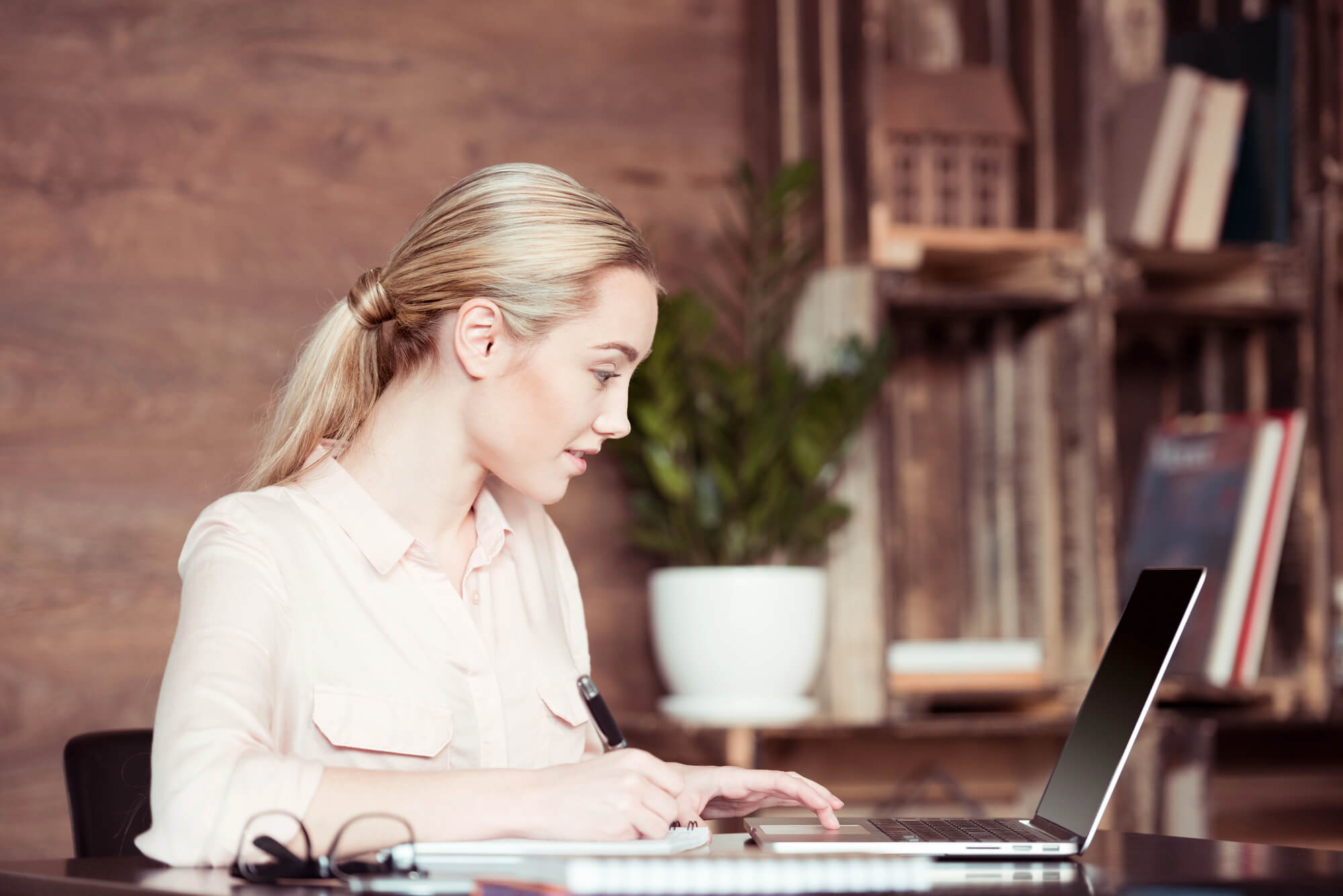 Unternehmerin am Laptop prüft, wie sichtbar ihr Unternehmen in KI-Antworten ist, und notiert die Ergebnisse